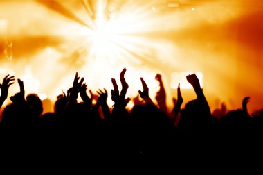 Parlak sahne ışıkları önünde konser kalabalığının siluetleri