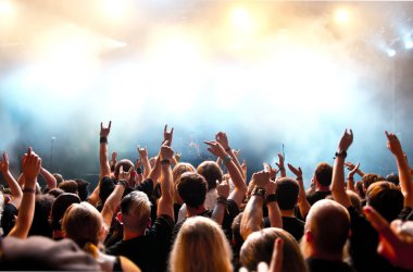 Parlak sahne ışıkları önünde konser kalabalığının siluetleri