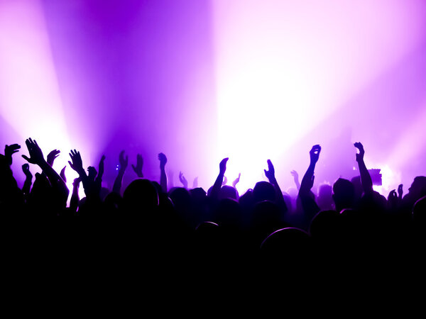 silhouettes of concert crowd in front of bright stage lights