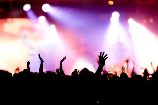 Parlak sahne ışıkları önünde konser kalabalığının siluetleri