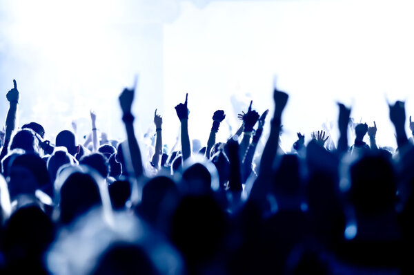 silhouettes of concert crowd in front of bright stage lights