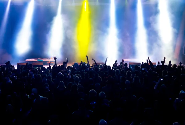 Parlak sahne ışıkları önünde konser kalabalığının siluetleri