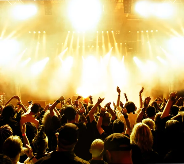 Parlak sahne ışıkları önünde konser kalabalığının siluetleri
