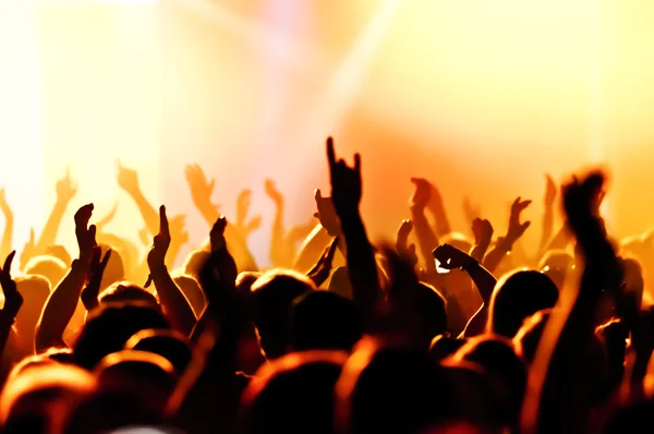 Parlak sahne ışıkları önünde konser kalabalığının siluetleri