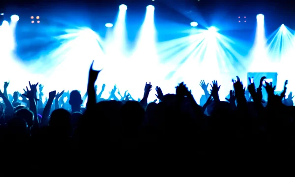 Parlak sahne ışıkları önünde konser kalabalığının siluetleri