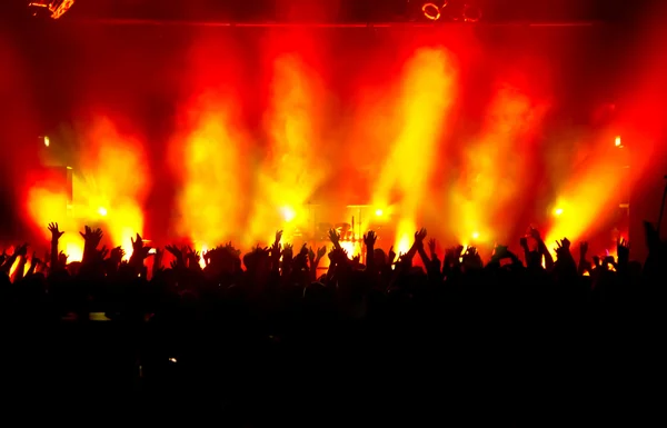 Parlak sahne ışıkları önünde konser kalabalığının siluetleri
