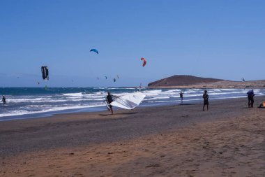 Tenerife 'deki El Medano plajında okyanus dalgaları üzerinde süzülen renkli uçurtmalarla spor meraklıları. Sörf ve aktif yaşam tarzı için mükemmel bir yer..