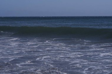 Büyük deniz dalgaları Tenerife 'nin volkanik kıyılarına doğru ilerliyor. Turkuaz su ve köpüklü güzel deniz manzarası Atlantik Okyanusu 'nun enerjisini gösteriyor..