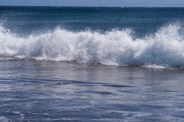 Büyük deniz dalgaları Tenerife 'nin volkanik kıyılarına doğru ilerliyor. Turkuaz su ve köpüklü güzel deniz manzarası Atlantik Okyanusu 'nun enerjisini gösteriyor..