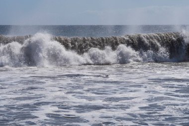 Büyük okyanus dalgaları Tenerife 'nin volkanik kıyılarına doğru akar. Turkuaz su ve köpükten oluşan güzel bir deniz manzarası Atlantik Okyanusu 'nun enerjisini somutlaştırır..