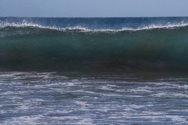 Büyük okyanus dalgaları Tenerife 'nin volkanik kıyılarına doğru akar. Turkuaz su ve köpükten oluşan güzel bir deniz manzarası Atlantik Okyanusu 'nun enerjisini somutlaştırır..