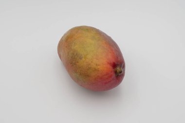 Beyaz arka planda pürüzsüz kırmızı ve sarı derili parlak olgun mango meyvesi.