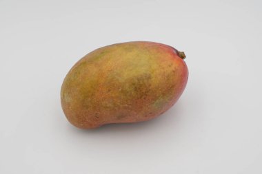 Beyaz arka planda pürüzsüz kırmızı ve sarı derili parlak olgun mango meyvesi.