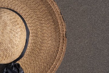 Volkanik siyah kumdaki hasır şapkayı kapat. Yaz sahili tarzı seyahat, rahatlama, moda ya da tatil konsepti. En küçük estetik resim.