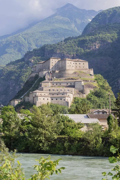 Ormanlı kayalık bir dağlık yamacın üzerindeki tarihi Bard Kalesi. Taş duvarlar ve savunma terasları İtalya 'da kültürel miras olarak bir dönüm noktası oluşturur..