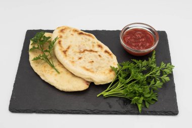 Kara taş tahtada maydanoz ve domates sosuyla servis edilen taze fırınlanmış taze ekmek. Geleneksel ev yapımı yiyecekler, doğal malzemeler ve köy tarzı..