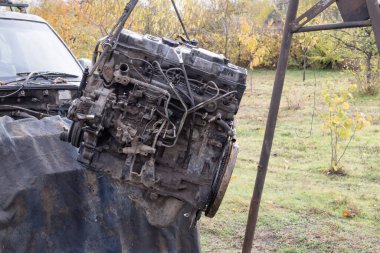 Eski arabanın motoru, açık hava tamir alanındaki bir asansörde kaldırıldı. Otomobil bakım, mühendislik ve restorasyonu temsil eden endüstriyel mekanik sahnesi.
