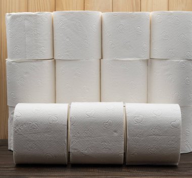 Ahşap arka plan, hijyen ve hijyen ürünleri bileşimi üzerine istiflenmiş beyaz tuvalet kağıdı ruloları