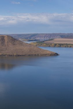 Dinyester Nehri 'ndeki Bakota Körfezi' nin azgın sonbahar manzarası. Pürüzsüz mavi sular, kuru tepeler ve berrak gökyüzünün altındaki tarlalar Podillia, Ukrayna 'nın doğal güzelliğini temsil ediyor..