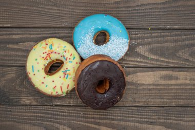 Kremalı, serpiştirilmiş, ahşap arka planda sıralanmış çeşitli renkli çörekler, tatlı tatlı pasta seti.