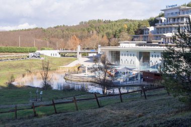 Açık havuzu olan modern termal spa merkezi, sıcak maden suyu ve sağlık alanında dinlenen insanlar. Manzaralı doğa manzarası, güneşli gün, tatil ve seyahat yeri.