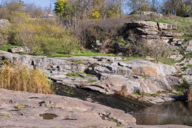 Katmanlı kaya kayalıkları ve engebeli bir kanyon yüzeyinde aşınma, katman ve ham jeolojik dokuları gösteren doğal kaya oluşumları..