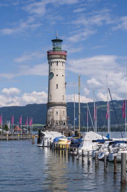 Almanya 'nın Constance Gölü limanındaki ünlü Lindau deniz feneri. Marinalı liman manzarası, yelkenli tekneler ve uzak Alp dağları..