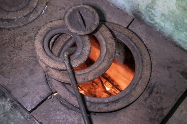 Eski köy odun sobası, yanan ateş ve demir pişirme halkaları.