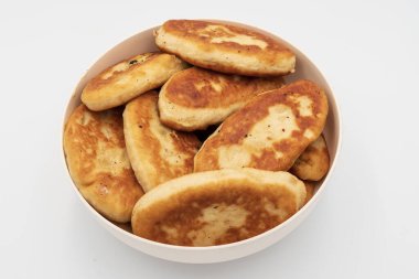 Bir kaseye istiflenmiş kızarmış hamur tatlısı yakın çekim. Beyaz arka planda doğal dokuyla izole edilmiş ev yapımı geleneksel yemekler..