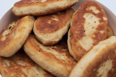 Bir kaseye istiflenmiş kızarmış hamur tatlısı yakın çekim. Beyaz arka planda doğal dokuyla izole edilmiş ev yapımı geleneksel yemekler..