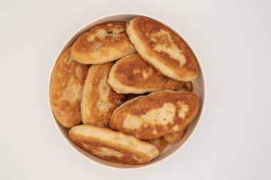 Bir kaseye istiflenmiş kızarmış hamur tatlısı yakın çekim. Beyaz arka planda doğal dokuyla izole edilmiş ev yapımı geleneksel yemekler..