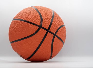 Beyaz arka planda izole edilmiş turuncu basketbol topu. Kapalı görünüm lastik dokuyu ve dikişleri gösteriyor, spor ve fitness kavramları için uygun.