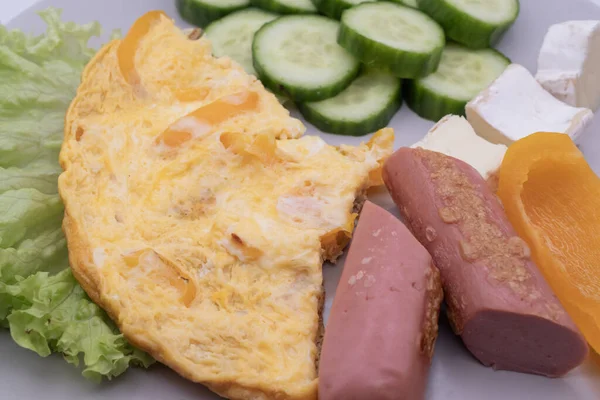 Sağlıklı kahvaltı tabağı omlet, dilimlenmiş sosis, peynir, salatalık ve marul. Basit ev yemekleri, dengeli beslenme ve günlük yiyecek konsepti..