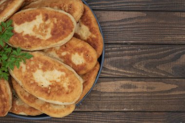 Tabakta servis edilen kıtır kıtır kızarmış patates turtası. Ahşap arka planda geleneksel ev yapımı hamur işi, konfor yemeği ve klasik mutfağı temsil ediyor..