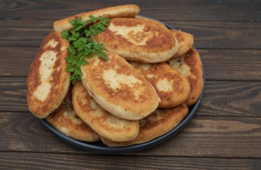 Tabakta servis edilen kıtır kıtır kızarmış patates turtası. Ahşap arka planda geleneksel ev yapımı hamur işi, konfor yemeği ve klasik mutfağı temsil ediyor..