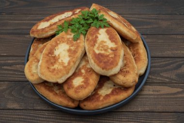 Tabakta servis edilen kıtır kıtır kızarmış patates turtası. Ahşap arka planda geleneksel ev yapımı hamur işi, konfor yemeği ve klasik mutfağı temsil ediyor..