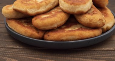 Tabakta servis edilen kıtır kıtır kızarmış patates turtası. Ahşap arka planda geleneksel ev yapımı hamur işi, konfor yemeği ve klasik mutfağı temsil ediyor..