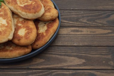 Tabakta servis edilen kıtır kıtır kızarmış patates turtası. Ahşap arka planda geleneksel ev yapımı hamur işi, konfor yemeği ve klasik mutfağı temsil ediyor..