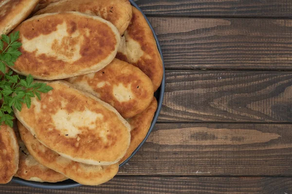 Tabakta servis edilen kıtır kıtır kızarmış patates turtası. Ahşap arka planda geleneksel ev yapımı hamur işi, konfor yemeği ve klasik mutfağı temsil ediyor..