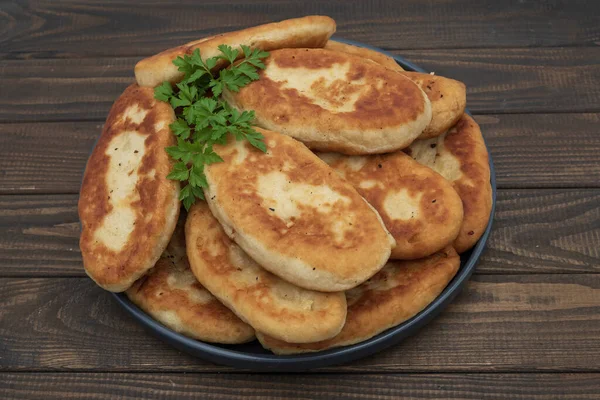 Tabakta servis edilen kıtır kıtır kızarmış patates turtası. Ahşap arka planda geleneksel ev yapımı hamur işi, konfor yemeği ve klasik mutfağı temsil ediyor..