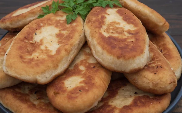 Tabakta servis edilen kıtır kıtır kızarmış patates turtası. Ahşap arka planda geleneksel ev yapımı hamur işi, konfor yemeği ve klasik mutfağı temsil ediyor..