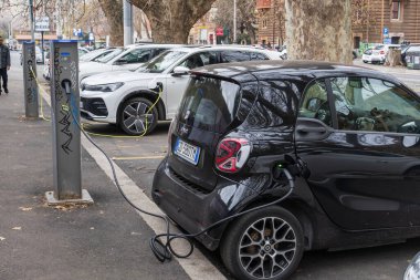 İtalya 'nın Roma kentsel caddesinde şarj istasyonuna bağlı elektrikli araçlar. Sürdürülebilir ulaşım kavramı.