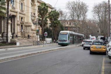 ATAC tramvayı, palmiye ağaçları, tarihi cephe ve günlük İtalyan şehir hayatı ile Roma 'nın sokak manzarası.