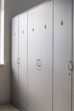 Temiz soyunma odasındaki numaralandırılmış dolaplar. Beyaz depo dolapları.