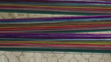 Yoğun yatay çizgiler halinde dizilmiş renkli ipliklerin yakın çekimleri, canlı, soyut bir tekstil deseni oluşturur.