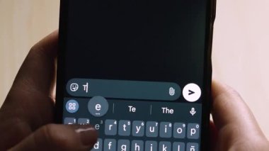 Akıllı telefonu tutan bir el, karanlık bir ekranda romantik bir mesaj (