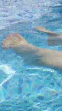 Açık mavi havuz suyuna batırılmış bir insan ayağına yakın çekim..