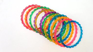 Beyaz arka planda dönen renkli plastik bilezikler, üst manzara, güzel moda aksesuarları.