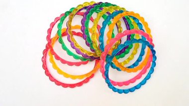 Beyaz arka planda dönen renkli plastik bilezikler, üst manzara, güzel moda aksesuarlar.