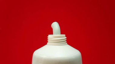 Kırmızı bir arka planda tüp içinden sıkışan saç aldırma kremi dokusu. Nemlendirici ya da cilt bakımı ürünü